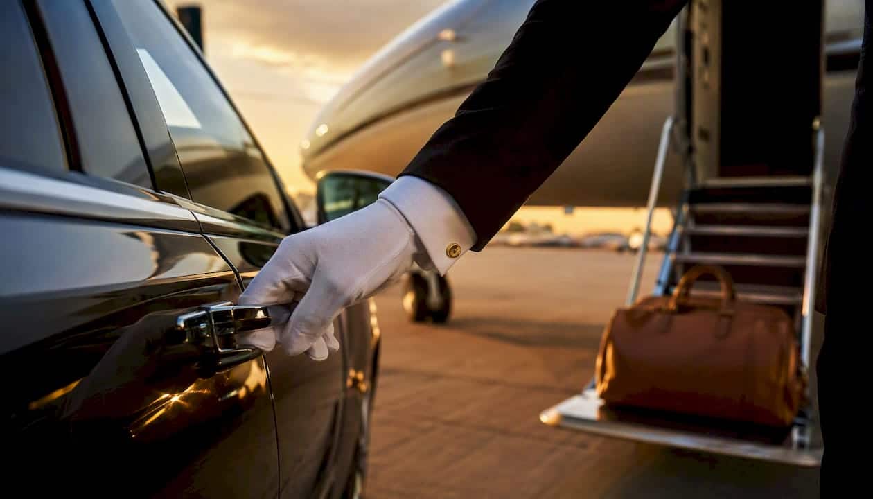 Chauffeur opening car door near private jet